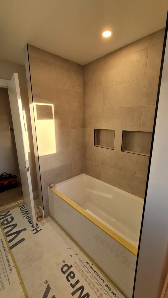 New tub-shower with large-format porcelain tile and a frameless glass sliding door