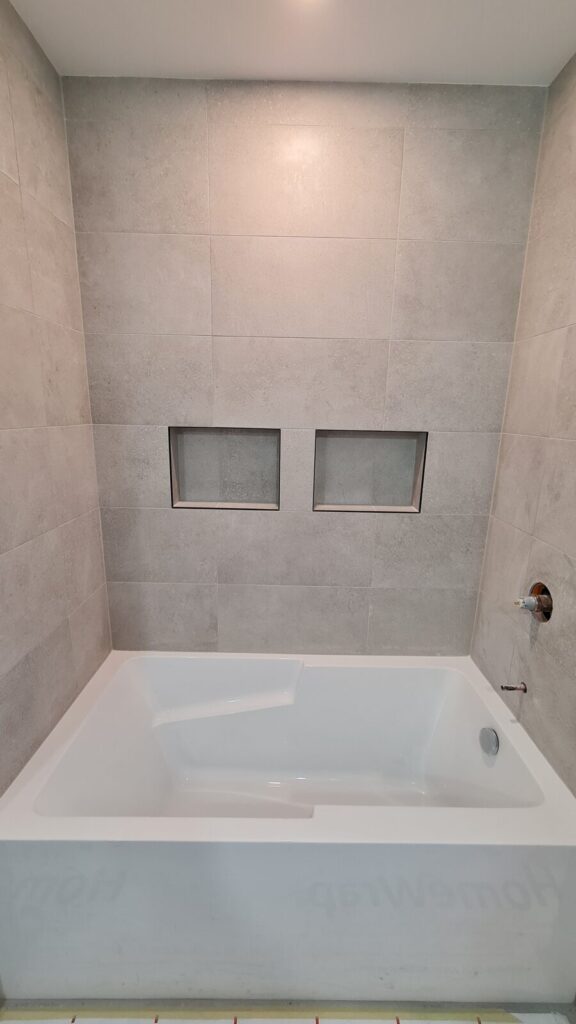 Modern bathtub with built-in tiled niches and large-format porcelain tile
